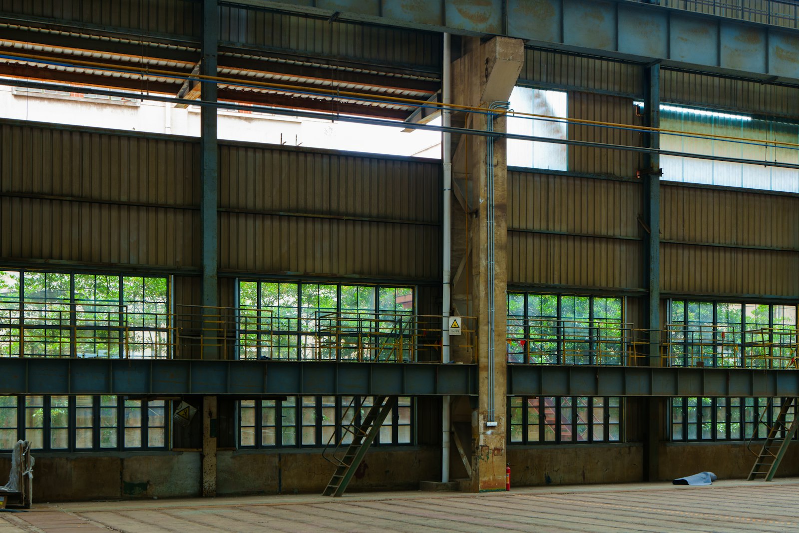 Large empty warehouse interior with steel beams and tall windows