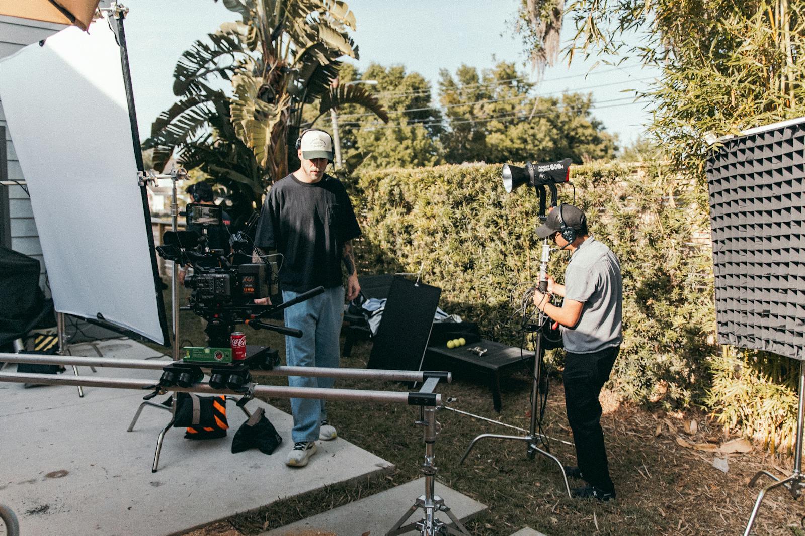 Film crew setting up a camera and lighting gear in an outdoor space